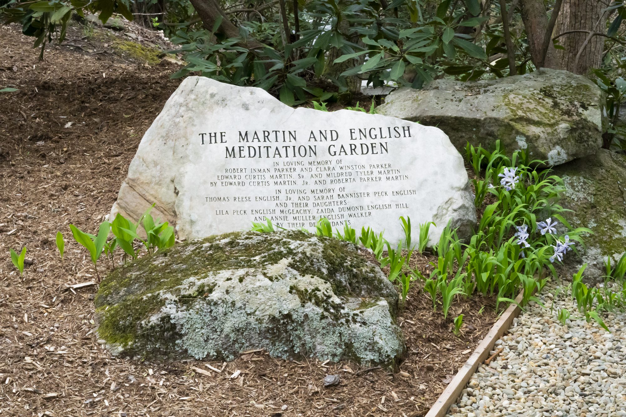 Engraved stone next to purple flowers at the columbarium.